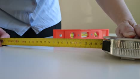 Woman-using-tape-measure-and-bubble-level-to-measure-and-calibrate-surface