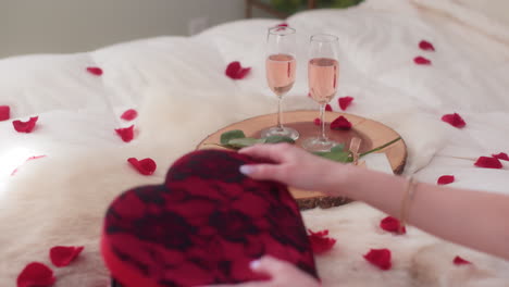 Sparkling-rose-wine-on-wooden-platter,-woman-grabbing-Valentine's-Day-chocolates