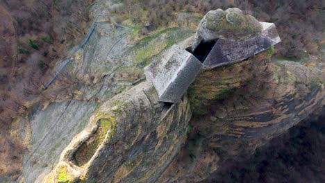 Aerial-view-of-a-unique-rock-formation-with-a-concrete-castle-structure-embedded,-aerial-view