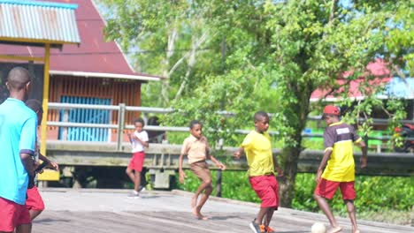 Papua-Kinder-Spielen-Fußball-Auf-Einem-Feld,-Das-über-Dem-Spielbrett-Im-Asmat-Bezirk-Von-Papua-Liegt