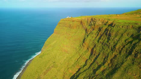 Aerial-view-of-green-mountain-face-wall-in-front-of-ocean-during-sunny-day-on-Madeira-Island---panorama-view