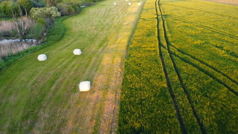 Drone-skims-over-a-Bavarian-field,-showcasing-cut-hay-bales