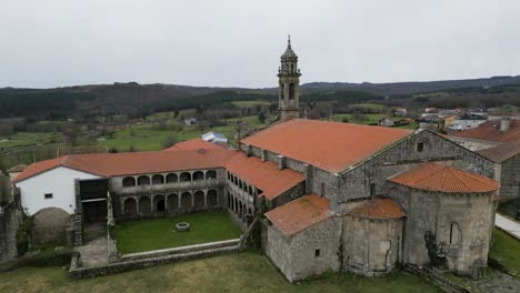 Drone-rises-above-Santa-Maria-de-Xunqueira-monastery-to-reveal-farmland-fields-of-Ourense