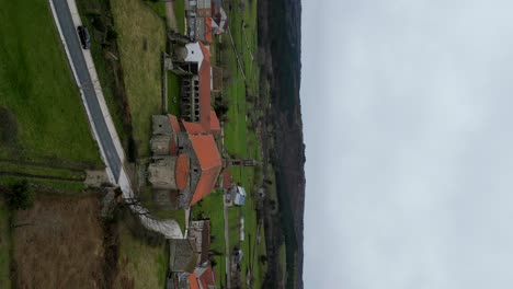 Panoramic-aerial-orbit-around-Santa-Maria-de-Xunqueira-monastery,-vertical