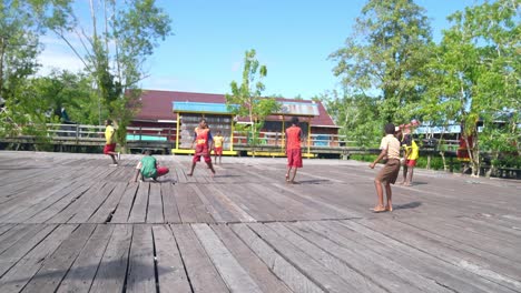 Papuanische-Grundschulkinder-Spielen-Fröhlich-Fußball-Auf-Dem-Asmat-District-Board-Field-In-Papua