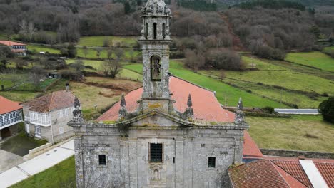 Drone-push-in-to-mossy-bell-tower-of-Santa-Maria-de-Xunqueira-monastery-church-with-birds