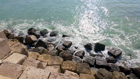 A-view-of-the-rocky-shoreline-with-shimmering-water-under-the-sunlight,-portraying-the-natural-coastal-beauty-of-Cadiz