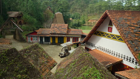 Ancient-Houses-in-Cu-Lan-Folk-Village,-Vietnam---Orange-roof-tiles-covered-with-winding-plants-and-moss