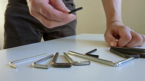 Man-selecting-hex-key-of-multiple-hex-key-tools,-close-up