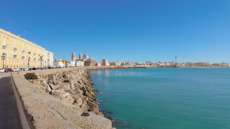 A-seaside-promenade-with-a-long-stretch-of-buildings-alongside-the-coastline,-reflecting-Cadiz's-coastal-charm-and-maritime-history