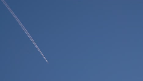 Airplane-flying-at-high-altitude-with-contrails-against-clear-blue-sky