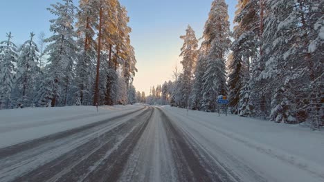 Winter-sun-reflects-on-ice-covered-rural-forest-roads-commute-travel-POV