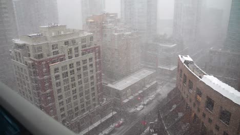 High-vantage-point-view-of-a-Robson-street-in-city-of-Vancouver-Canada-during-a-white-strong-snow-storm-blizzard-blowing-sideways-surrounded-by-big-buildings-and-skyscrapers