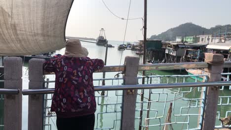 Old-lady-looks-out-onto-the-ocean-from-Tai-O-on-Lantau-Island,-Hong-Kong