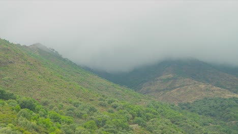 Fog-and-dark-clouds-flowing-above-mountains-of-Estepona,-time-lapse-view