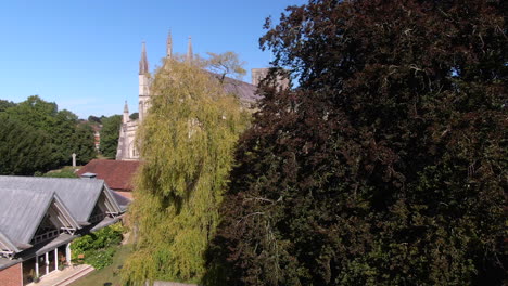 Aufsteigender-Drohnenschuss,-Der-Die-Kathedrale-Von-Winchester-Hinter-Bäumen-Im-Sommer-In-Hampshire,-Großbritannien,-Enthüllt