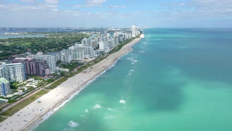 Drone-view-along-Collins-Avenue-in-Miami,-revealing-modern-hotel-buildings-that-line-the-ocean-front,-offering-stunning-water-views
