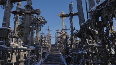 Ancient-religious-crosses-with-a-beautiful-vanishing-point-and-landscape-in-the-background,-on-the-Hill-of-Crosses-in-Lithuania,-cinematic-shot-in-slow-motion