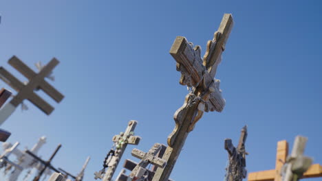 Ancient-religious-crosses-with-rosaries-at-a-Dutch-angle-under-a-blue-sky,-cinematic-shot-in-slow-motion