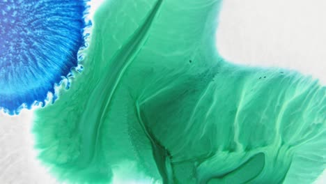 Close-up-of-vibrant-blue-and-green-ink-patterns-merging-in-water,-creating-an-abstract-art-effect