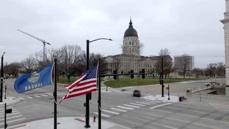 Edificio-Del-Capitolio-Del-Estado-De-Kansas-Con-Banderas-Ondeando-En-El-Viento-En-Topeka,-Kansas-Con-Video-De-Drones-Subiendo