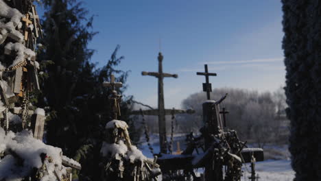 Ancient-Christian-crosses-in-the-middle-of-the-forest-surrounded-by-pines-and-trees,-illuminated-by-the-sun's-rays-in-a-close-up,-under-a-blue-sky,-cinematic-shot-in-slow-motion