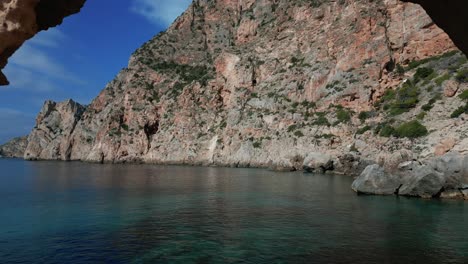 Die-Drohne-Fliegt-Durch-Ein-Loch-In-Einer-Felsklippe-Am-Meer-Auf-Ibiza,-Spanien.-Luftaufnahmen-In-4K
