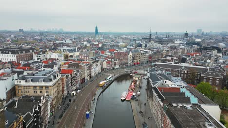 Die-Drohne-Fliegt-An-Einem-Bewölkten-Tag-In-Amsterdam,-Niederlande,-über-Dem-Rokin-Kanal-Und-Der-Straße-Mit-Blick-Auf-Das-Stadtzentrum.-Luftaufnahmen-In-4K