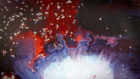 Rote-Und-Blaue-Tinte-Verschmelzen-Im-Wasser-Mit-Glitzernden-Partikeln-Und-Schaffen-So-Eine-Dynamische-Und-Abstrakte,-Fließende-Kunstszene