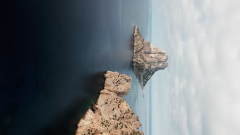 Die-Drohne-Fliegt-Seitwärts-über-Das-Meer-Und-Blickt-Auf-Es-Vedrà,-Die-Kleine-Felseninsel-In-Vertikaler-Position-Auf-Ibiza,-Spanien.-Luftaufnahmen-In-4K