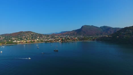 Flying-over-a-bay-filled-with-sailing-yachts-and-boats-anchored-in-the-calm-water-off-the-coast-of-Zihuatanejo,-Mexico