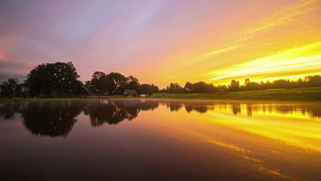 Morgentau-Und-Wolken-Ziehen-über-Einen-See,-Bevor-Ein-Orangefarbener-Sonnenaufgang-Den-Tag-Ankündigt