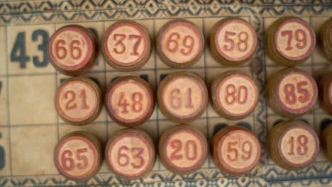 Cinematic-close-up-smooth-zoom-out-shot-of-a-Bingo-wooden-barrels,-woody-figures,-on-a-old-numbers-textured-background,-vintage-board-game,-professional-lighting,-slow-motion-120-fps