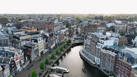 Die-Drohne-Fliegt-über-Dem-Stadtzentrum-Und-Blickt-Seitwärts-Auf-Den-Muntplein,-Während-Die-Sonne-In-Amsterdam-Scheint.-Luftaufnahmen-In-4K-In-Den-Niederlanden