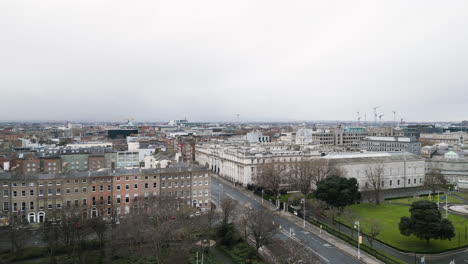 Parallax-drone-shot-of-Merrion-Square-Park-Area-with-a-beautiful-cityscape-in-Dublin,-Ireland-during-month-of-January