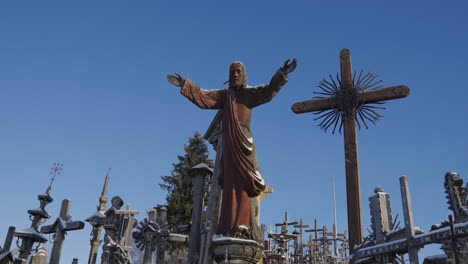 Beautiful-sculpture-of-Jesus-Christ-preaching,-surrounded-by-crosses-on-the-Hill-of-Crosses-in-Lithuania-in-the-middle-of-winter