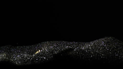 Fallende-Goldene-9-mm-Kugeln-Auf-Silberschwarzem-Sand-Mit-Schwarzem-Hintergrund,-Nahaufnahme-In-Zeitlupe
