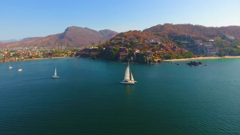 Drone-video-slowing-orbiting-around-a-catamaran-sailboat-cruising-around-a-beautiful-urban-point-in-Mexico-in-a-beautiful-ocean-bay