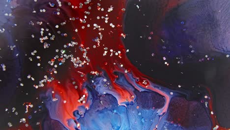 Tinta-Roja-Y-Azul-Vibrante-Girando-En-Agua-Con-Partículas-Brillantes,-Una-Fusión-Abstracta-Que-Crea-Un-Efecto-Fascinante