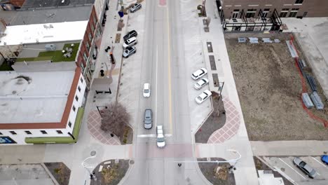 Intersection-with-cars-moving-in-downtown-Topeka,-Kansas-with-overhead-drone-video-tilting-up