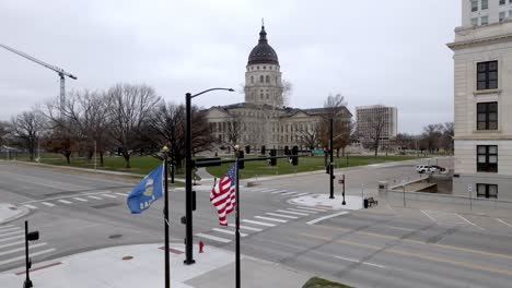 Kansas-State-Capitol-Gebäude-Mit-Im-Wind-Wehenden-Flaggen-In-Topeka,-Kansas-Mit-Drohnenvideostall
