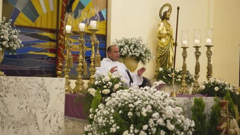 An-adult-priest-dressed-in-his-white-robe-prays-during-a-ceremony-in-a-Catholic-church