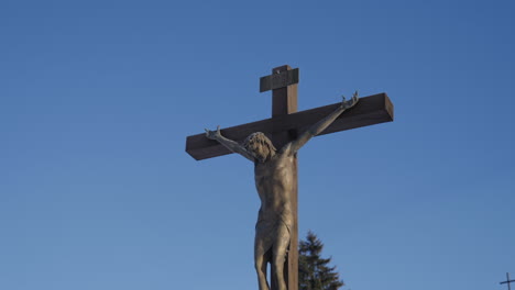 Cruz-Cristiana-Detallada-Con-Jesús-Crucificado-Bajo-Un-Cielo-Azul-Al-Aire-Libre