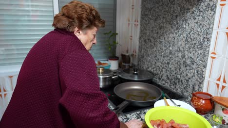 Old-granny-cooking-in-the-kitchen-with-olive-oil-in-a-fried-pan