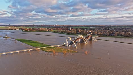 Aerial-orbit-drone-shot-to-the-right-at-the-weir-of-Driel-during-high-water-levels-with-the-doors-open-and-with-the-town-of-Driel-in-the-background