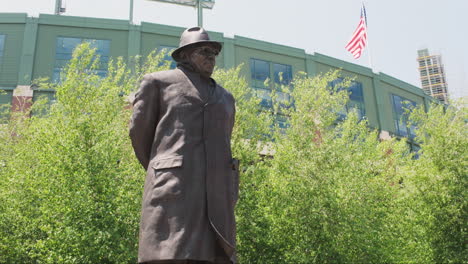Statue-of-coach-Vince-Lombardi-with-Lambeau-Field-and-an-American-flag-in-the-background