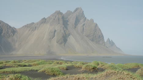 A-breathtaking-Mount-Vestrahorn-view-on-the-edge-of-an-ocean-with-a-windswept-grassland-in-the-foreground