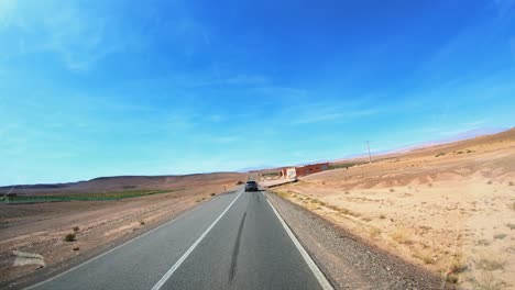 Viaje-En-Automóvil-Desde-La-Vista-De-Hiperlapso-En-Marruecos,-Cruzando-La-Tierra-Desierta-En-La-Carretera-Durante-El-Día-Y-Llegando-A-Ait-Benhaddou