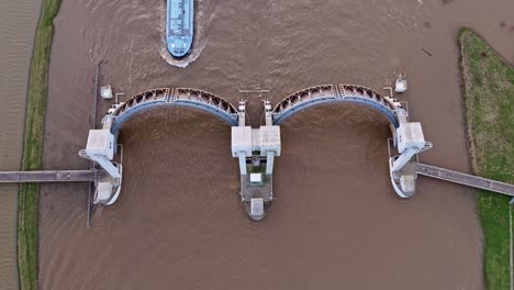 Top-down-drone-shot-of-the-weir-of-Driel-with-a-cargo-ship-passing-thru-the-wier-during-high-water-levels