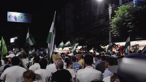 City-street-night-rally,-people-wave-flags-for-Santa-Cruz-de-la-Sierra